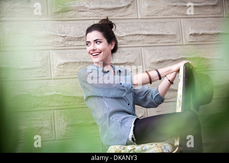 Junge Frau draußen sitzen auf Stuhl Stockfoto