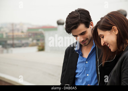 Paar freigegebenen Ohrstöpsel auf Stadt Dach anhören Stockfoto