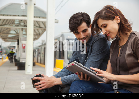 Paar, die Zeitung zu lesen, während der Wartezeit am Bahnhof, Los Angeles, Kalifornien, USA Stockfoto