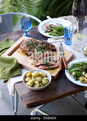 Esstisch mit gegrillte Kräuter Kruste Lamm und grünen Frühling Stockfoto