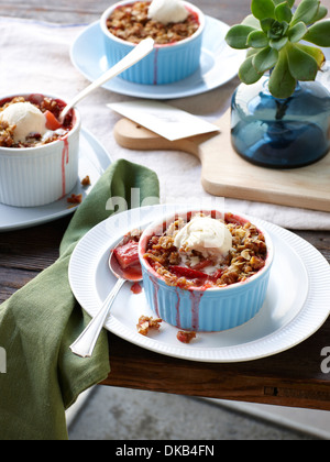 Stillleben mit Rhabarber, Apfel und Erdbeere crumble mit Eis Stockfoto