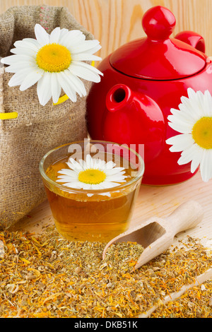 gesunden Kamillentee, rote Teekanne und Säckchen mit Gänseblümchen Stockfoto