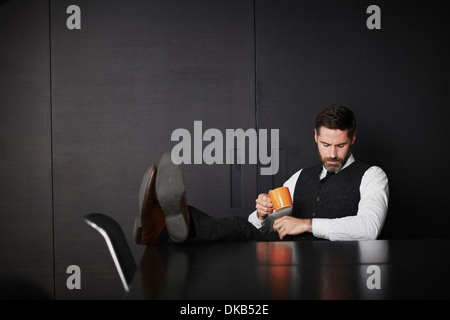 Geschäftsmann mit Füße hoch halten Kaffee Stockfoto