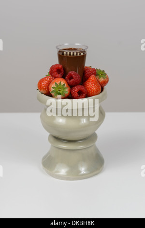 Stillleben mit Schokolade Dessert mit Rapberries und Erdbeeren auf einer Keramikschale vor einem grauen Hintergrund Stockfoto