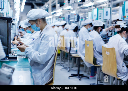 Gruppe der Arbeitnehmer bei der kleinen Teilefertigung Fabrik in China, tragen von Schutzkleidung, Hüte und Masken Stockfoto