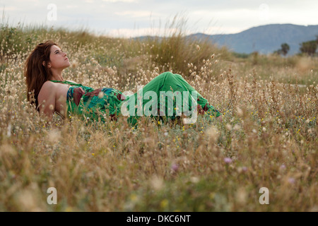 Schwangere Frau, die im Feld liegen Stockfoto