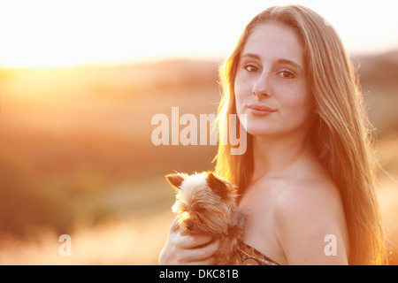 Teenager im Feld bei Abenddämmerung Holding Haushund Stockfoto