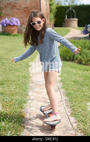 Mädchen Skateboard Weg im Garten Stockfoto