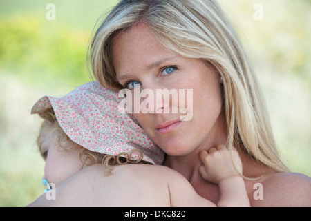 Mutter umarmt Kleinkind tragen Sonnenhut Stockfoto