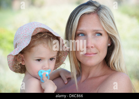 Mutter umarmt Kleinkind tragen Sonnenhut Stockfoto