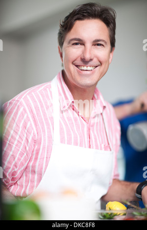 Reifer Mann in der Küche trägt Schürze Stockfoto