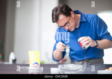 Reifer Mann mischende Schüssel Löffel Backpulver hinzufügen Stockfoto