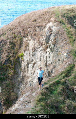 Mitte Erwachsene Frau jogging am Küstenweg, Thurlestone, Devon, UK Stockfoto