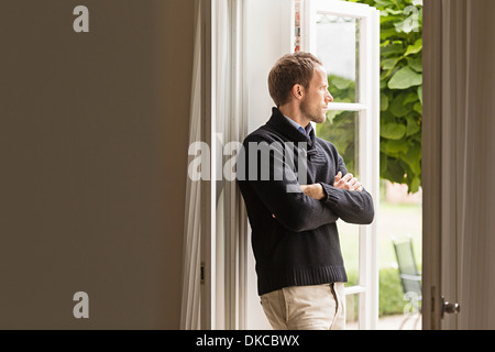 Mitte erwachsener Mann aus Fenster Arme gefaltet Stockfoto