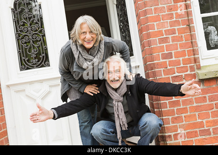 Älteres paar durch vordere Tür, Mann mit offenen Armen Stockfoto