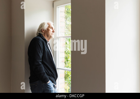 Porträt von senior woman Blick aus Fenster Stockfoto