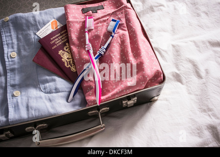 Offenen Koffer auf Bett mit UK Pässe und rosa und blauen Zahnbürsten Stockfoto