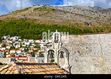 Trio von Glocken und historische Mauer in Dubrovnik mit klassischen rot gefliesten Dächer der Stadt. Riesiger Berg über der Stadt im Hintergrund. Stockfoto