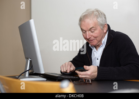 Ältere Mann zu Hause mittels PC Stockfoto