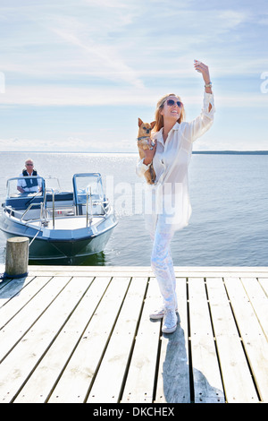 Junge Frau fotografieren sich mit Hund auf Pier, Hotels, Schweden Stockfoto