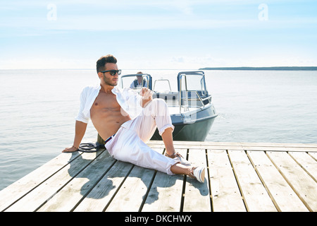 Junger Mann sitzt auf Pier, Hotels, Schweden Stockfoto