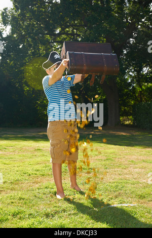 Junge verkleidet als Pirat Entleerung Gold aus Schatztruhe im Garten Stockfoto