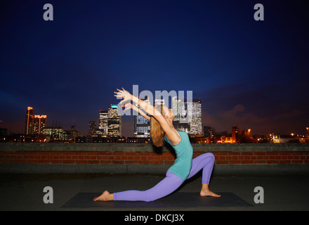 Mitte Erwachsene Frau Yoga auf Stadt auf dem Dach in der Nacht zu tun Stockfoto