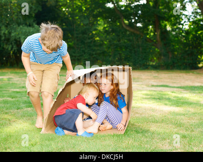 Geschwister im Karton im Garten versteckt Stockfoto