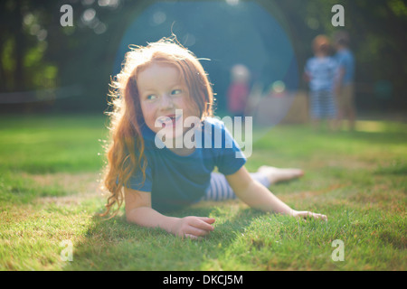 Fröhliches junges Mädchen liegen auf dem Rasen im Garten Stockfoto