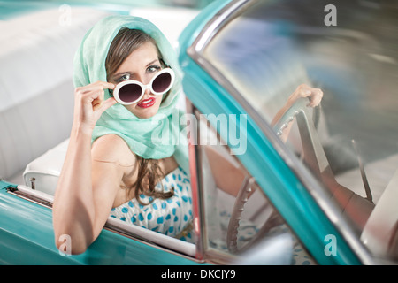 Frau im Kopftuch Senkung Sonnenbrille im Vintage-Cabrio Stockfoto