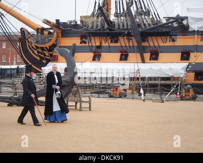 Akteure im viktorianischen Kostüm gehen vorbei HMS Victory in Portsmouth Historic Dockyard, England Stockfoto
