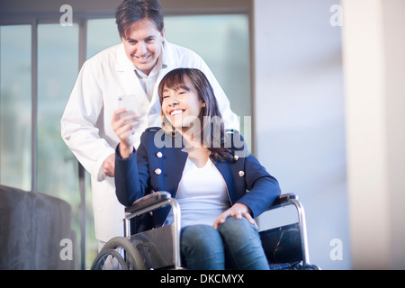 Frau im Rollstuhl, unterstützt von Krankenpfleger Stockfoto