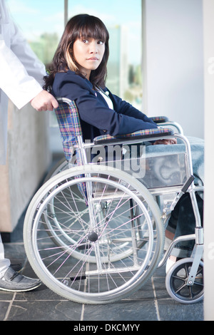 Frau im Rollstuhl, unterstützt von Krankenpfleger Stockfoto