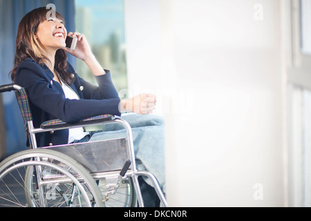 Frau im Rollstuhl mit Handy Stockfoto