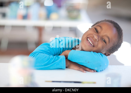 Glückliches Mädchen Arme gekreuzt auf Tisch Stockfoto