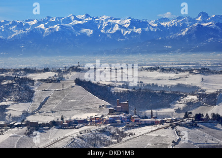 Typische kleine italienische Stadt auf den Hügeln, bedeckt mit Schnee und Berge Gipfeln im Hintergrund im Piemont, Norditalien. Stockfoto