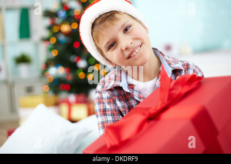 Porträt der fröhliche junge mit großen roten Geschenkbox Blick in die Kamera am Heiligen Abend Stockfoto