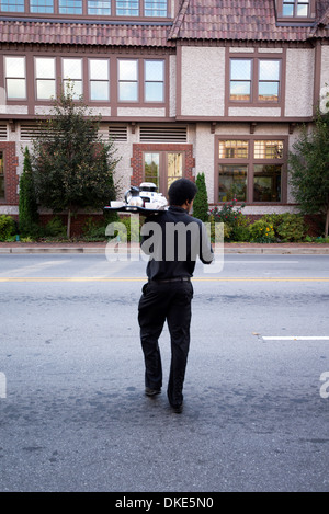 Mann mit Lebensmittel-Fach auf der anderen Straßenseite vom roten Hirsch Inn Grand Bohemian Hotel in der Innenstadt von Asheville, North Carolina Stockfoto