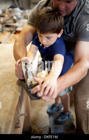 Vater mentoring Sohn auf Zimmerei in Boot Werkstatt Stockfoto