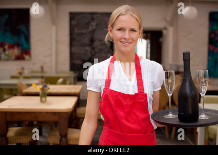 Porträt von Kellnerin mit Tablett mit Wein und Gläser im café Stockfoto