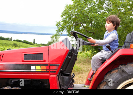 Männliche Kleinkind vorgibt, dem Traktor im Garten Stockfoto