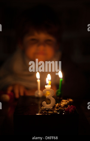 Bei Kerzenschein männliche Kleinkind betrachten Geburtstagstorte Stockfoto