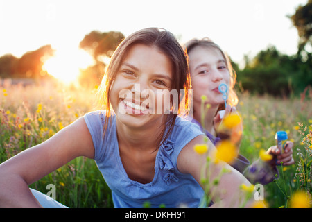 Porträt von Mädchen sitzen im Feld, eine Seifenblasen Stockfoto