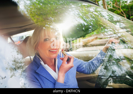 Reife Frau Auftragen von Lippenstift in Auto Stockfoto