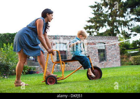 Mutter drängt Sohn auf Dreirad Stockfoto