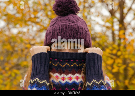 Porträt der jungen Frau im Park mit Jumper versteckt Gesicht Nahaufnahme Stockfoto