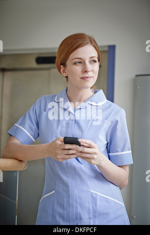 Krankenschwester mit Handy vor Krankenhaus Aufzug Stockfoto