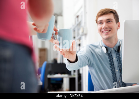 Frau jungen Mann Kaffee im Büro zu geben Stockfoto