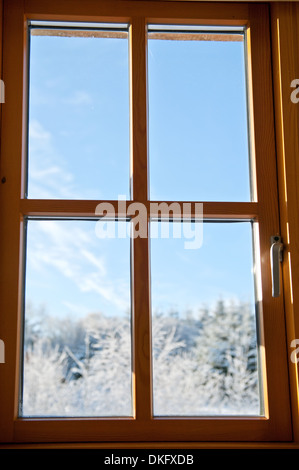 Sitzen in einem warmen Raum, der Blick aus dem Fenster auf den ersten Schnee in diesem Winter früh an einem frostigen Morgen Stockfoto