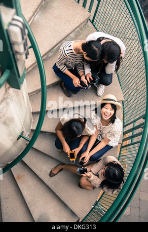 Fünf junge Frauen sitzen auf Stufen Blick auf smartphones Stockfoto